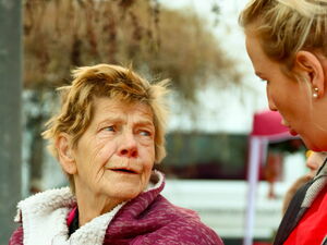 Ältere Frau steht neben jüngere Frau in roter AWO Kleidung. Sie sprechen miteinander.