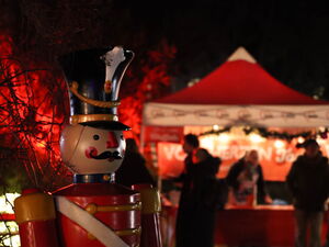 Eine große Nussknacker-Figur im Vordergrund. Dahinter ein beleuchteter AWO Pavillon und Menschen (unscharf).