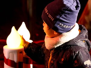 Zwei große LED Kerzen werden von einem kleinen Kind berührt, bestaunt.