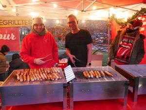 2 fröhliche Männer am Würstchen-Grill.